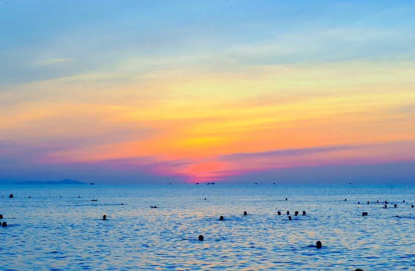 People Swimming On Sea During Golden Hour