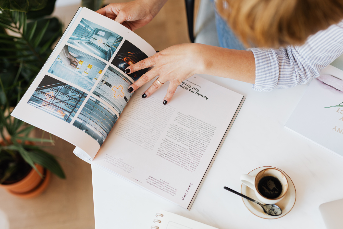 Crop woman reading magazine and drinking coffee